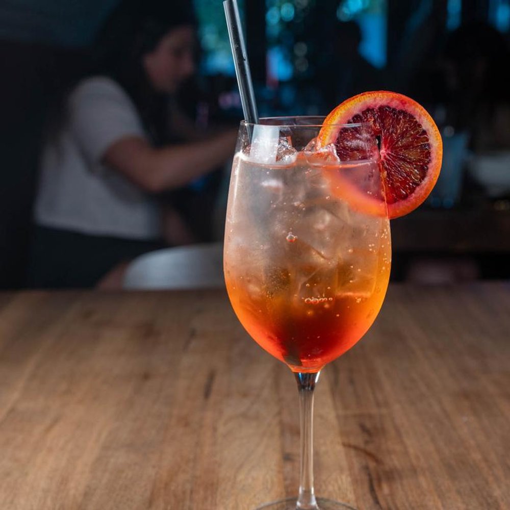 Aperol Spritz Cocktail On A Table With People In The Background.