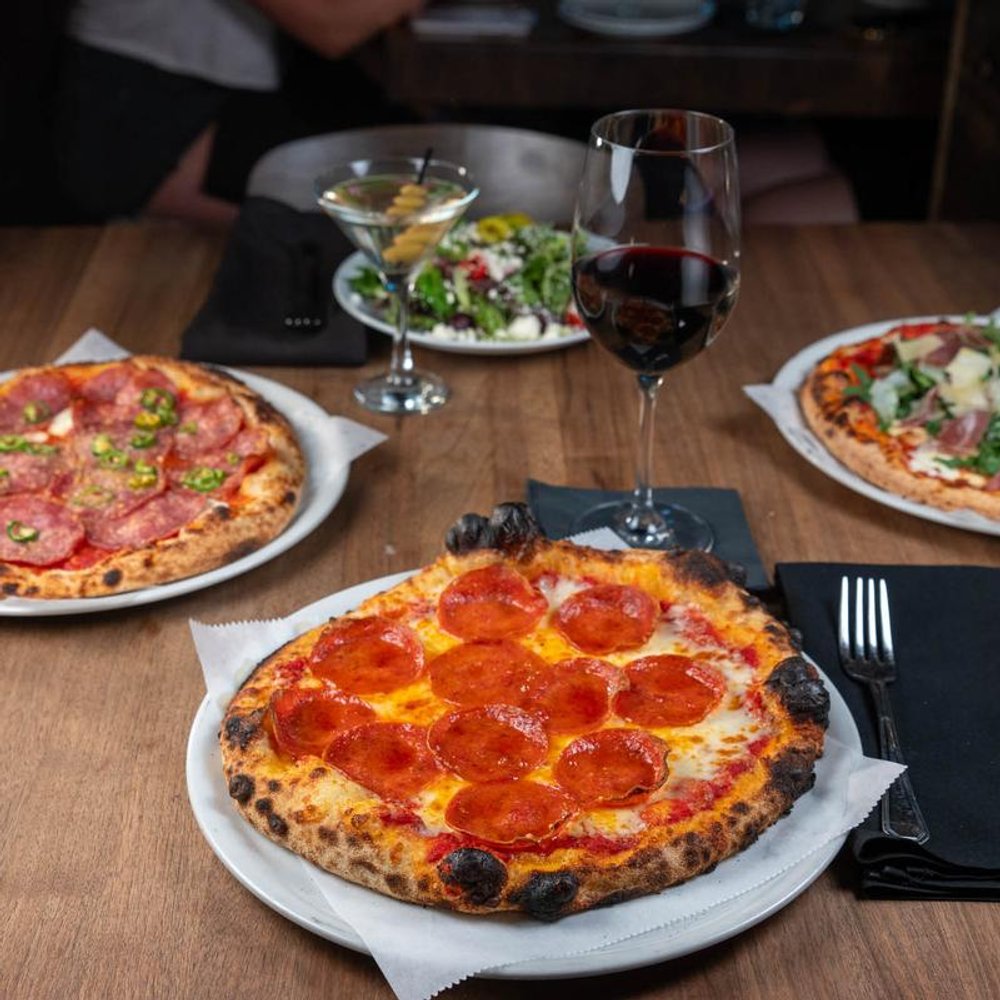 Assorted Pizzas On A Table With A Glass Of Red And White Wine.