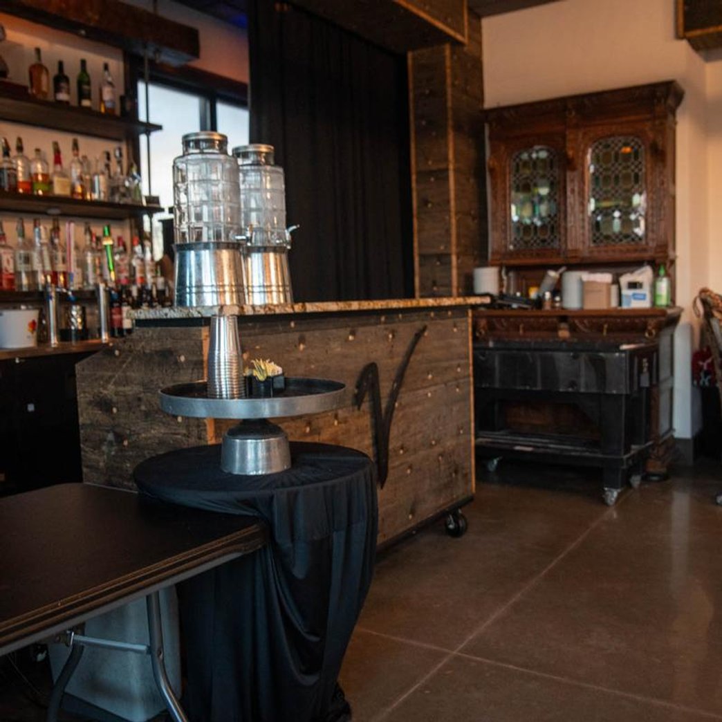 Bar with a cabinet shelves of liquor and beverage dispensers on a counter