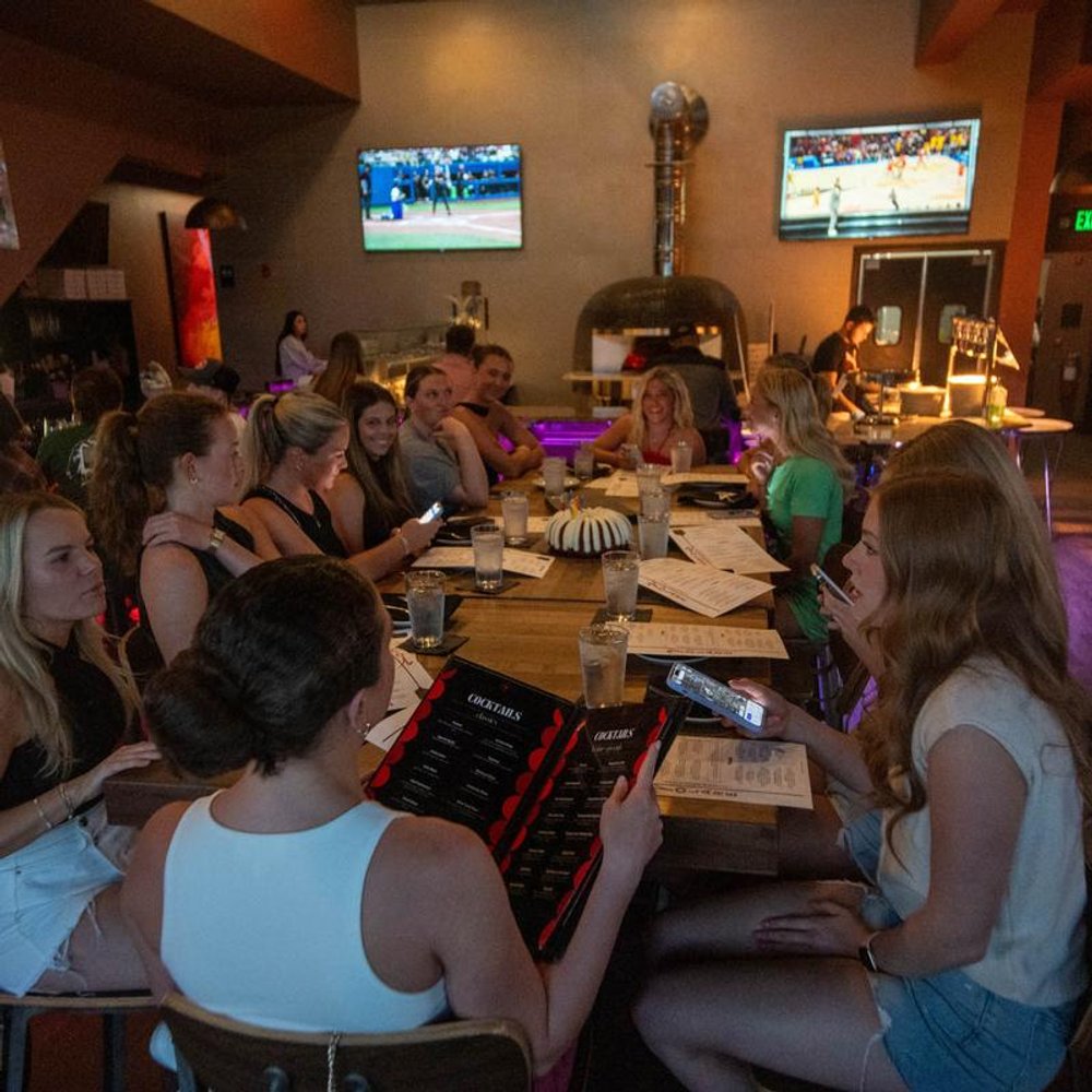 Big Group Seated At A Long Table Looking At The Menus.