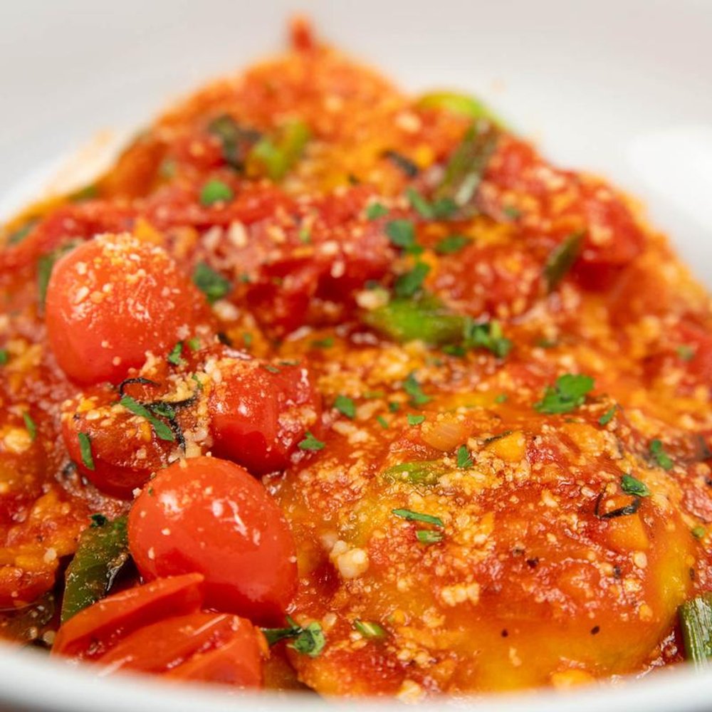 Burrata Ravioli Topped With Tomato Basil Sauce Parmesan And Herbs.