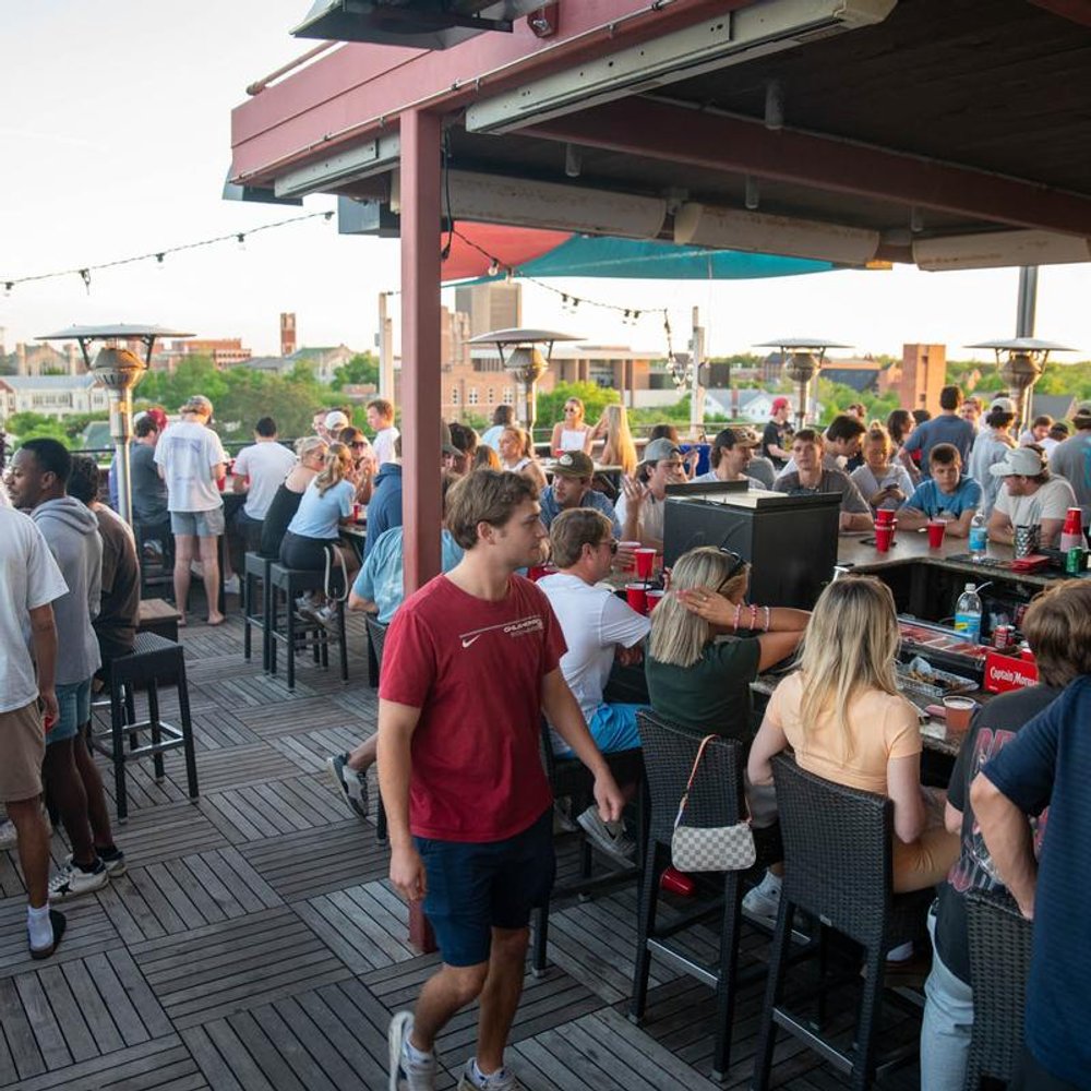 Busy Bar Terrace With Guests Enjoying Nice Weather Over Drinks.