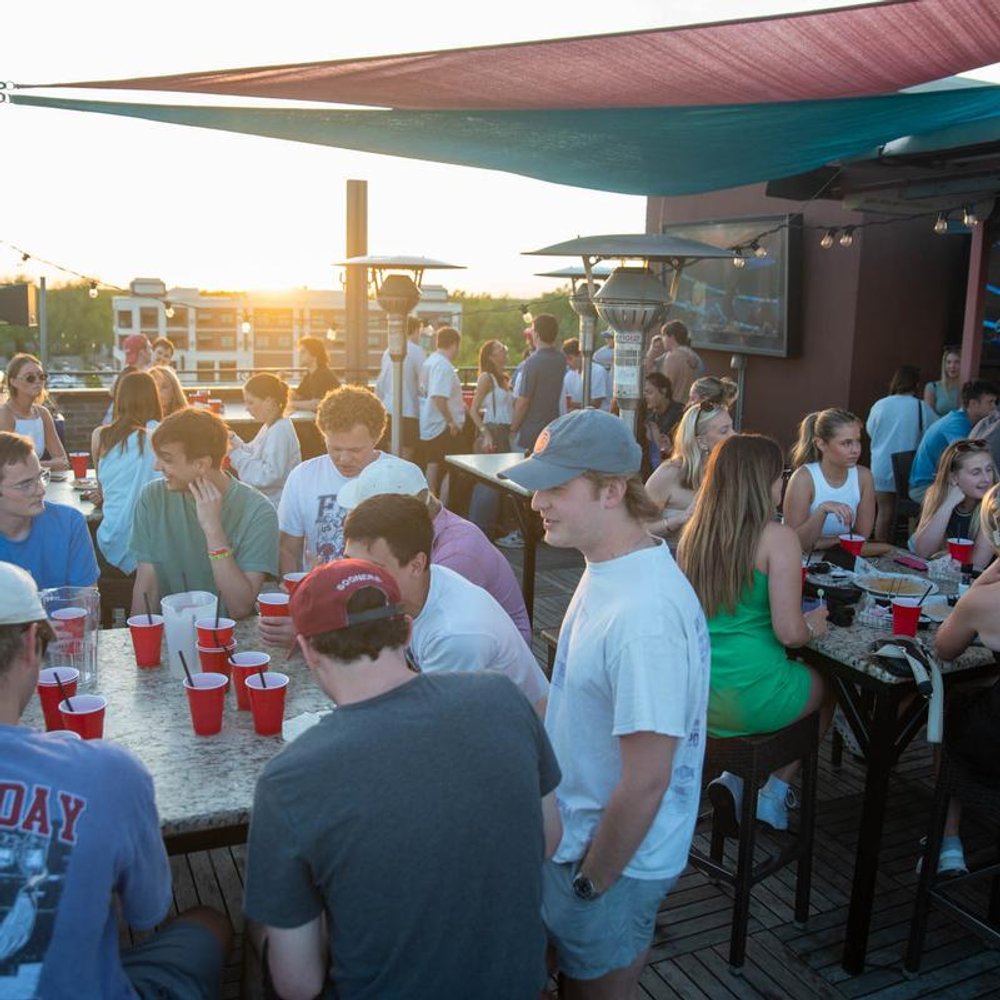 Busy Bar Terrace With Guests Socializing And Enjoying Sunset.