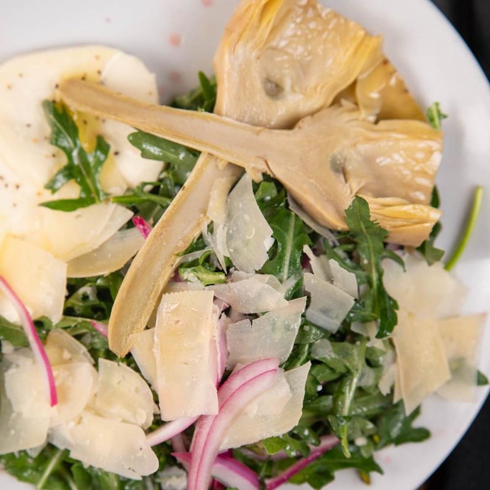 Close Up Of Arugula Artichoke Salad With Mozzarella Shaved Parmesan And Onion.