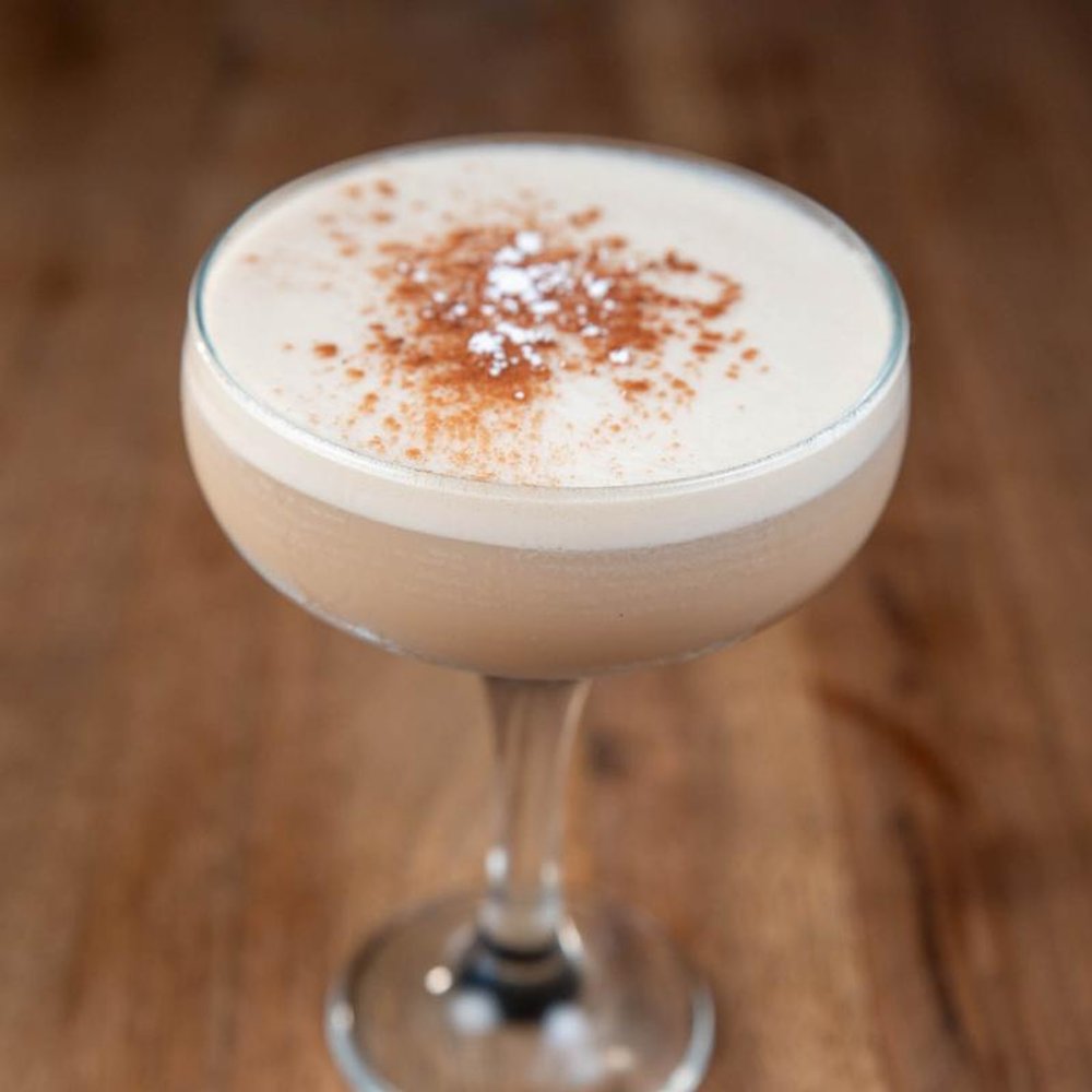 Espresso Martini Cocktail Sprinkled With Cinnamon On A Wooden Surface.