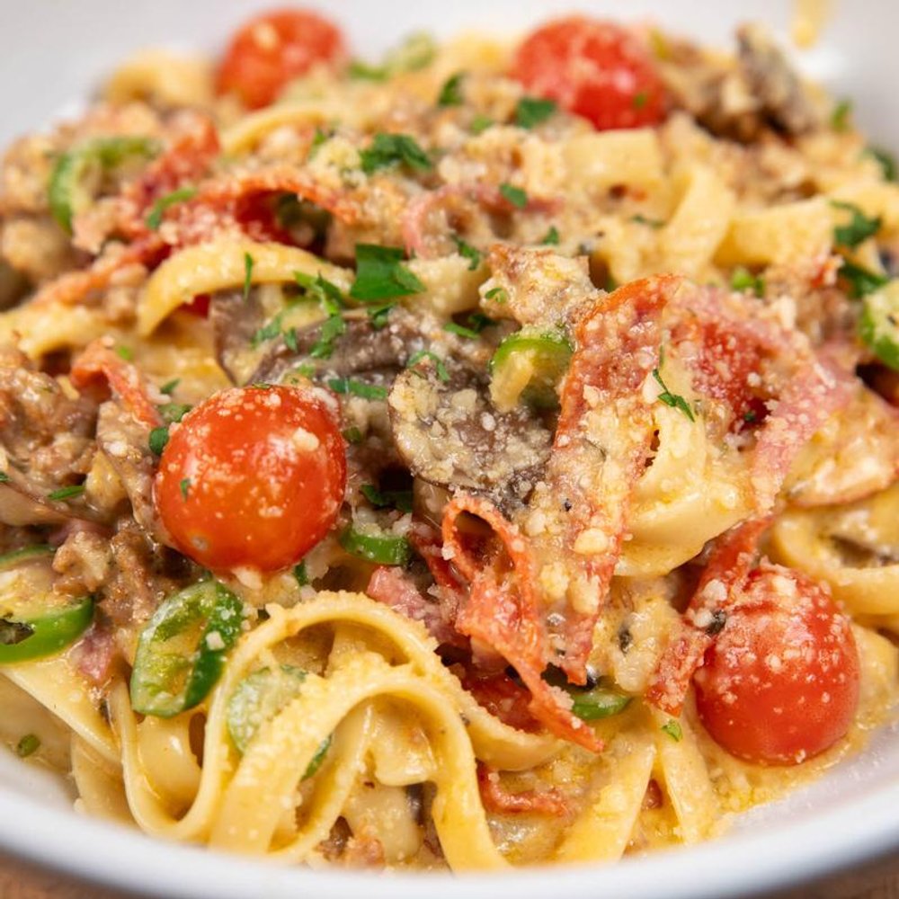 Fettuccini Pasta With Various Meats Tomatoes Parmesan And Chilis Closeup.