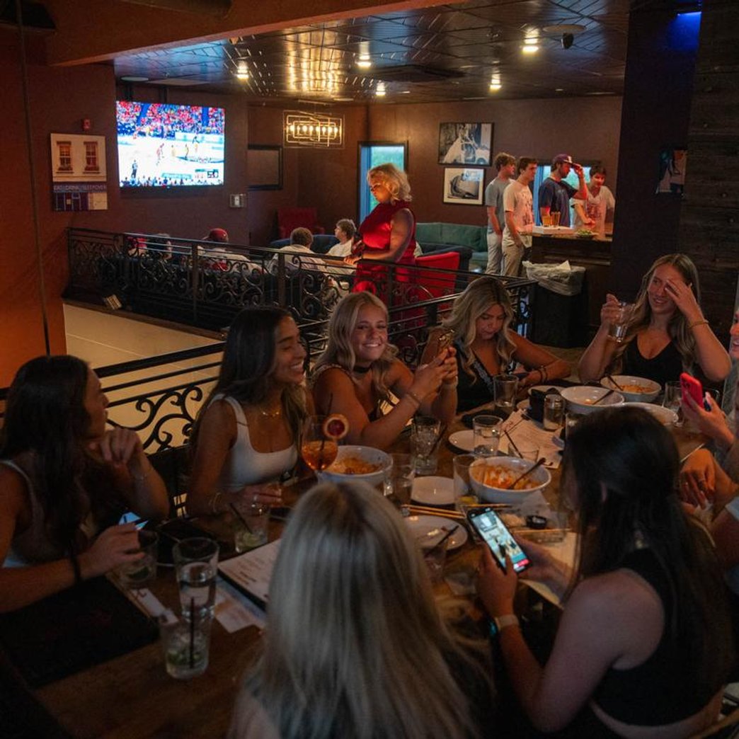 Group of people sitting at a table with drinks and empty plates