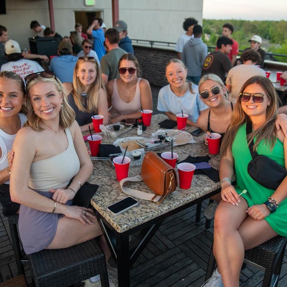 Group Of People Sitting At An Outdoor Table Posing For A Photo.