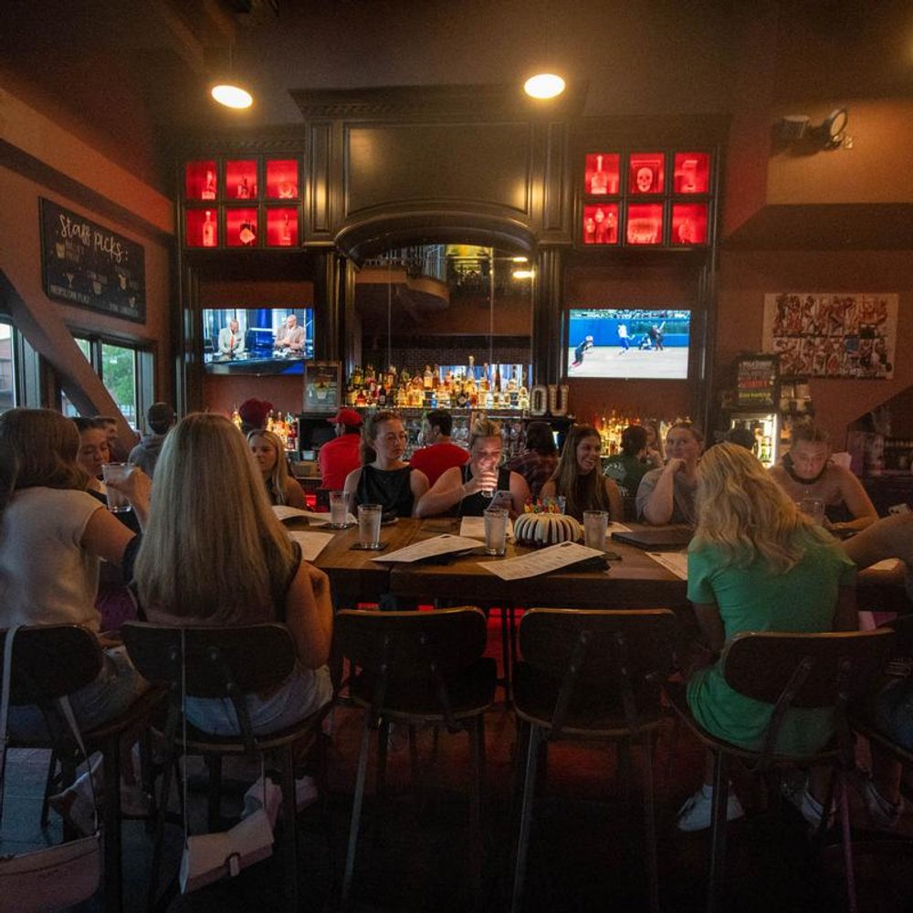 Guests Seated At A Sports Bar With Tvs.