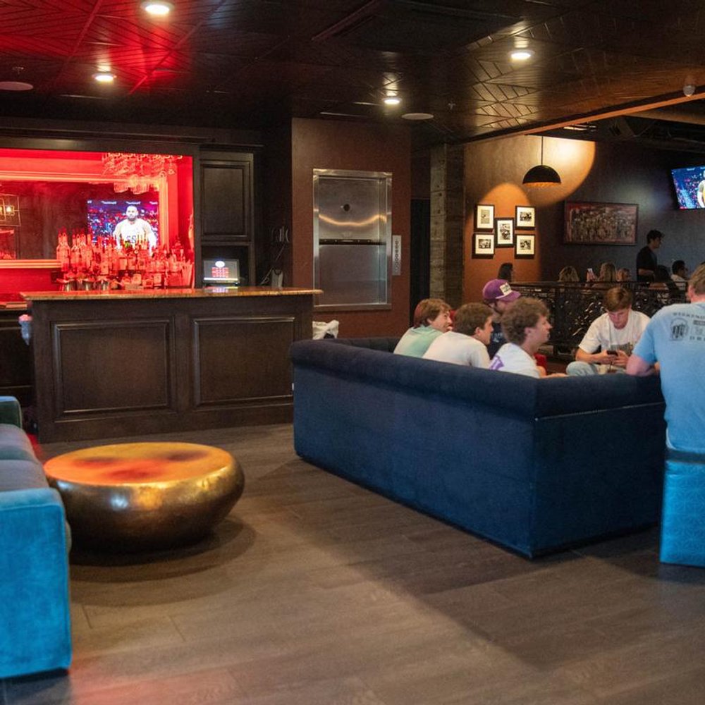 Lounge Area With A Bar Sofas Guests And Tvs.