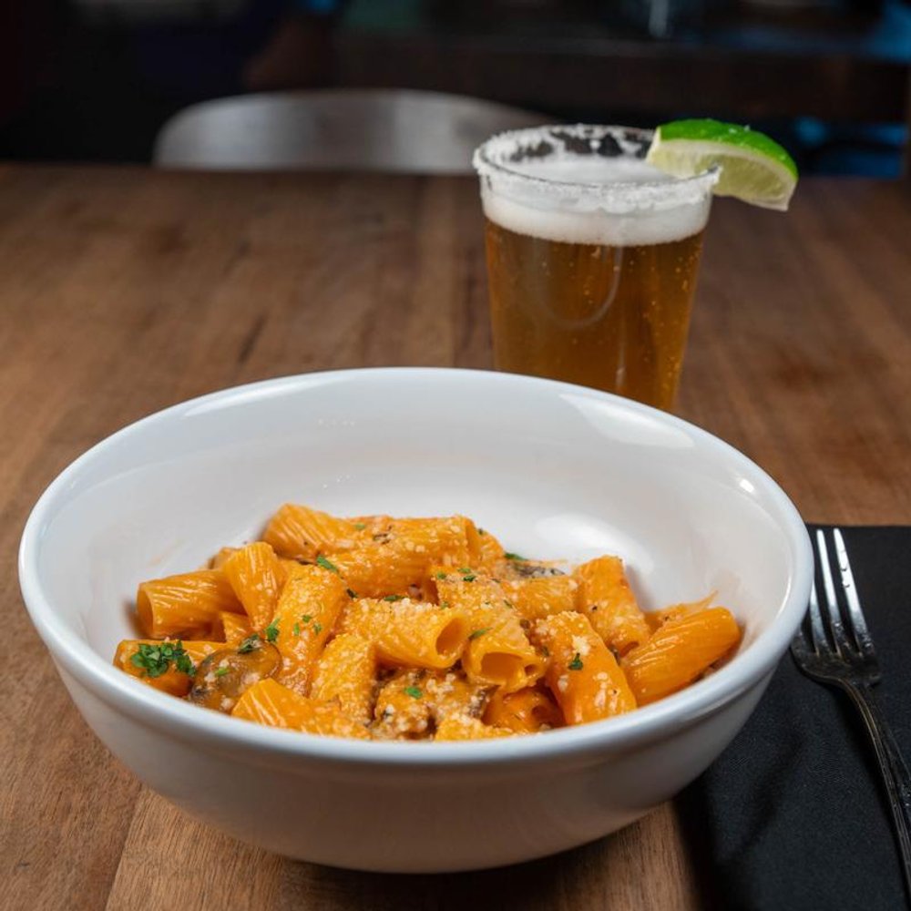 Mushroom Rigatoni Served On A Table With A Glass Of Beer.