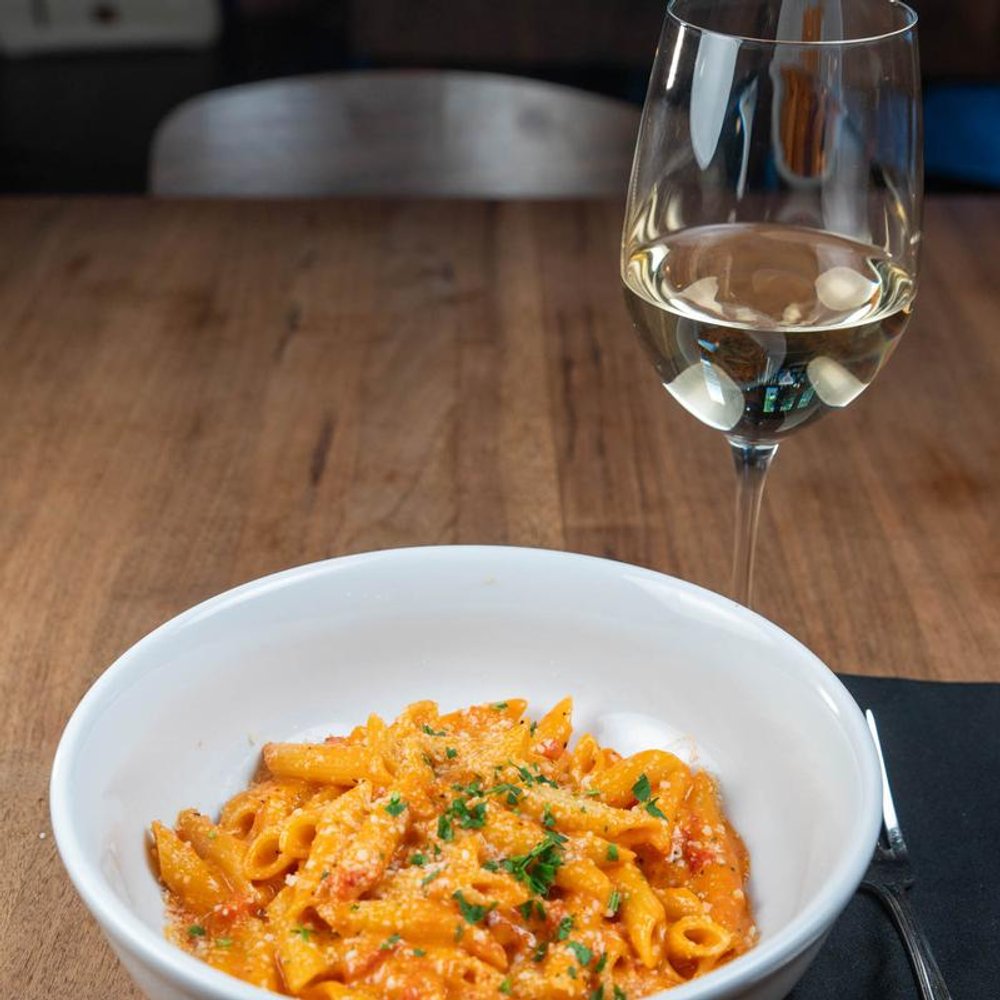 Penne Vodka Pasta With A Glass Of White Wine On A Table.