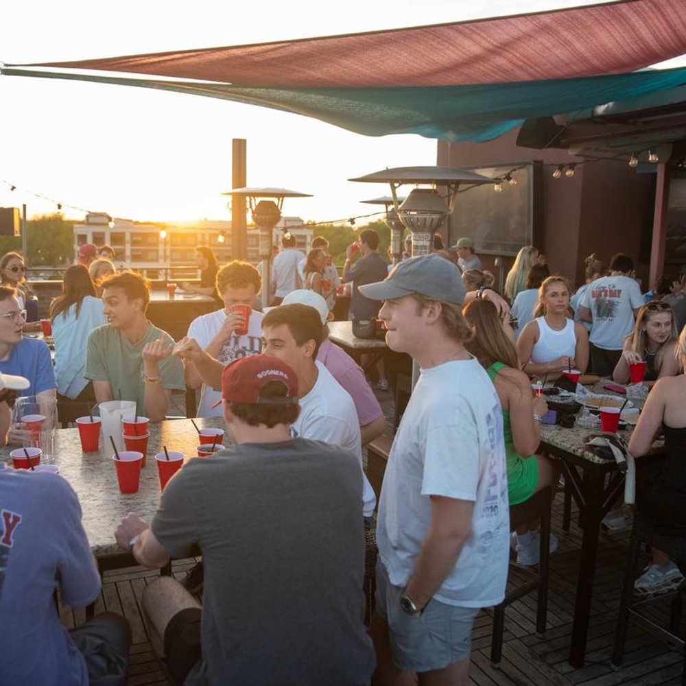 People Enjoying The Afternoon Sun Over Drinks On A Bar Terrace.