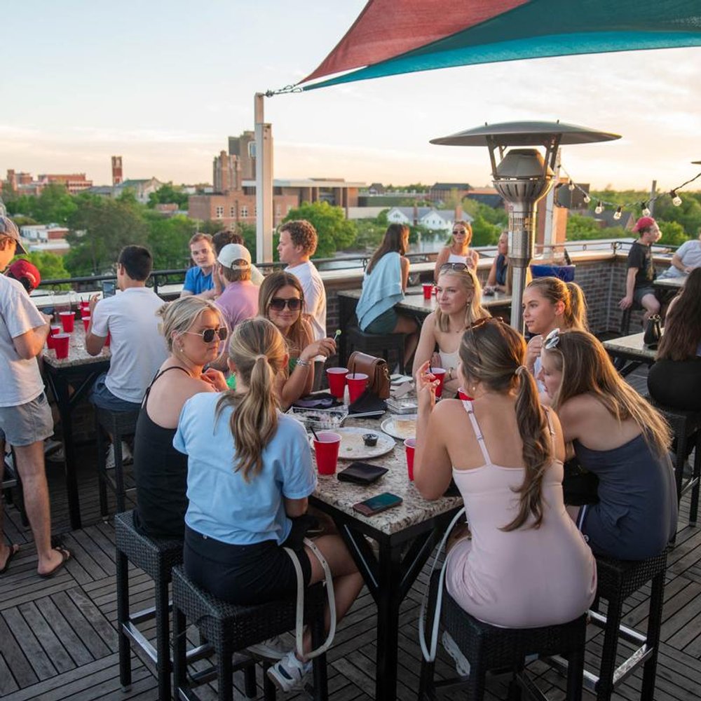 People Enjoying Themselves On A Bar Terrace Over Drinks In The Afternoon Sun.