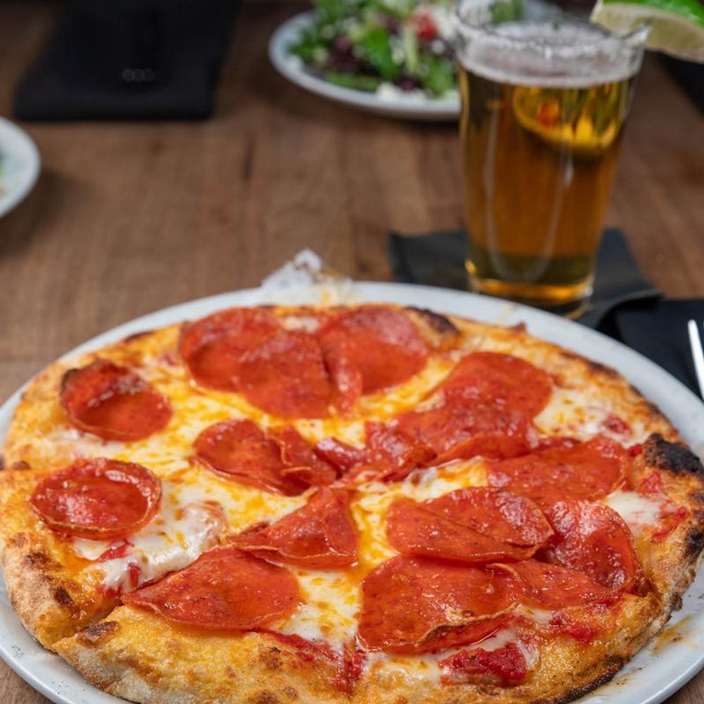 Pepperoni Pizza Up Front With A Beer And A Salad In The Background.