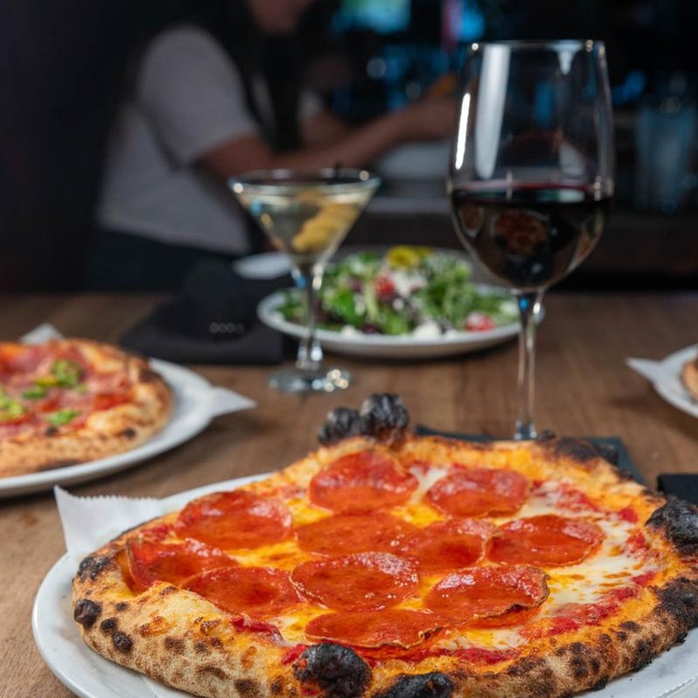 Pizzas And Salads On A Table With A Glass Of Red Wine And A Martini.