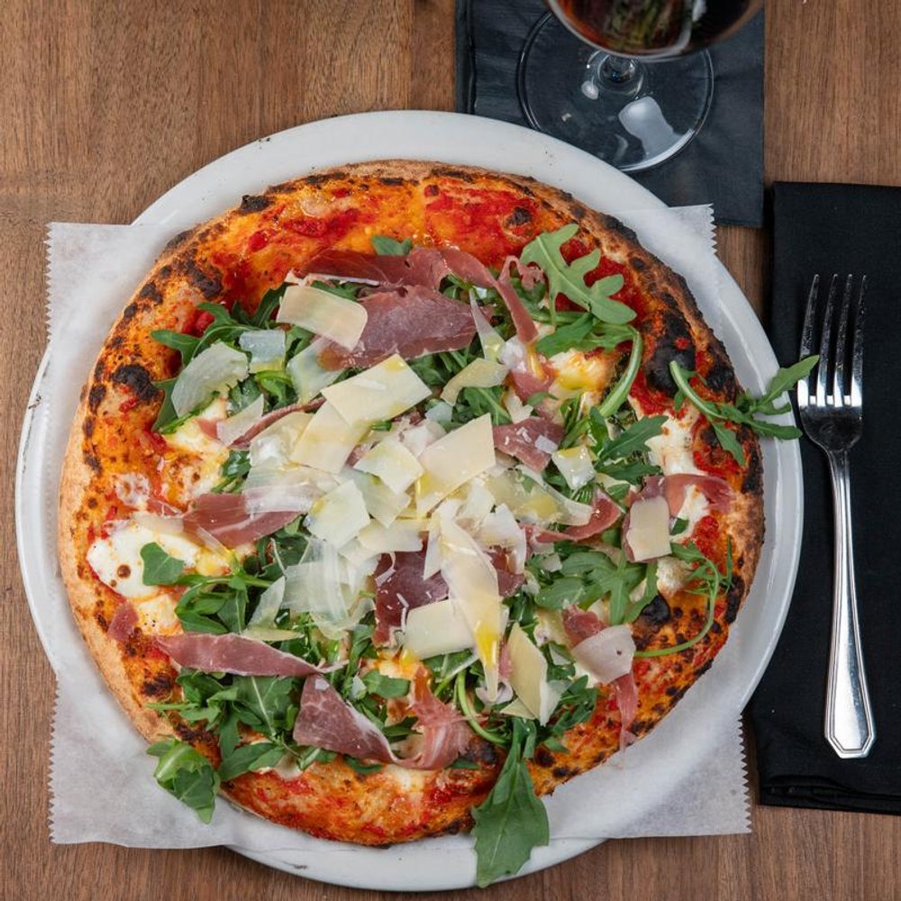 Prosciutto Pizza With Arugula Red Sauce And Parmesan.