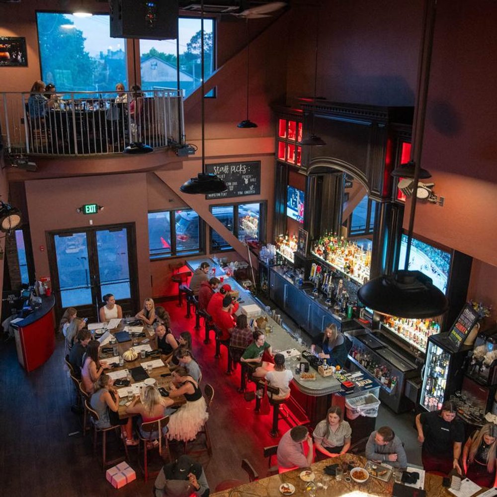 Restaurant With A Mezzanine Well Stocked Bar And Guests Seated At Tables.