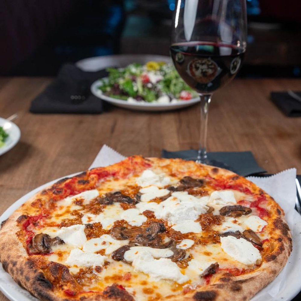 Ricky Ricotta Pizza Served With A Glass Of Wine Other Dish In The Background.