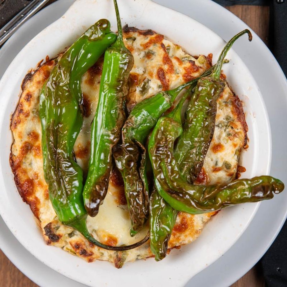 Roasted Shishito Peppers Served Over Jalapeno Artichoke Dip.