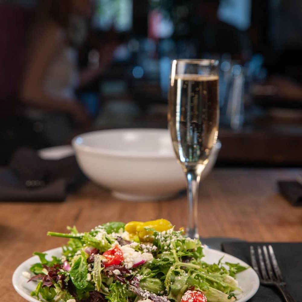 Salad With Greens Cheese And Tomatoes On A Table With Champagne.