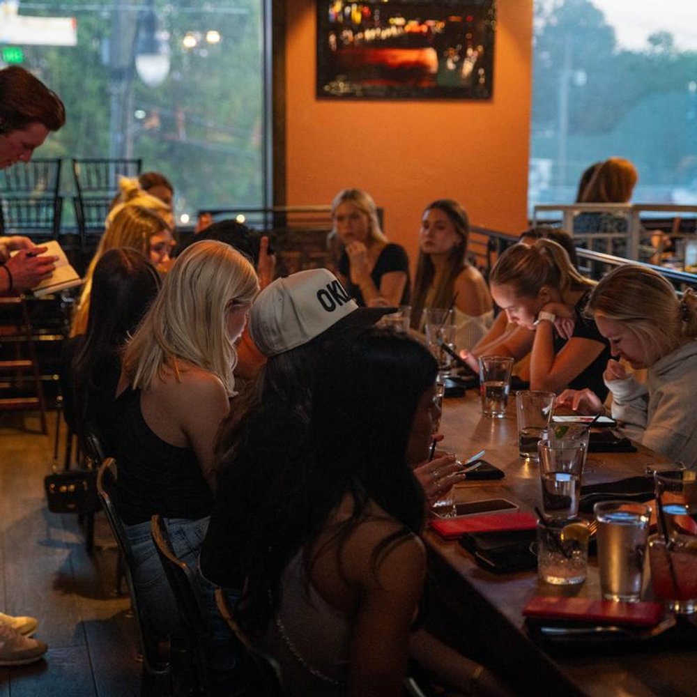 Server Taking Orders From A Big Group Seated At A Table With Drinks.