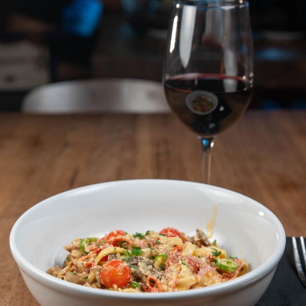 Spicy Fettuccine Pasta Served On A Table With A Glass Of Red Wine.