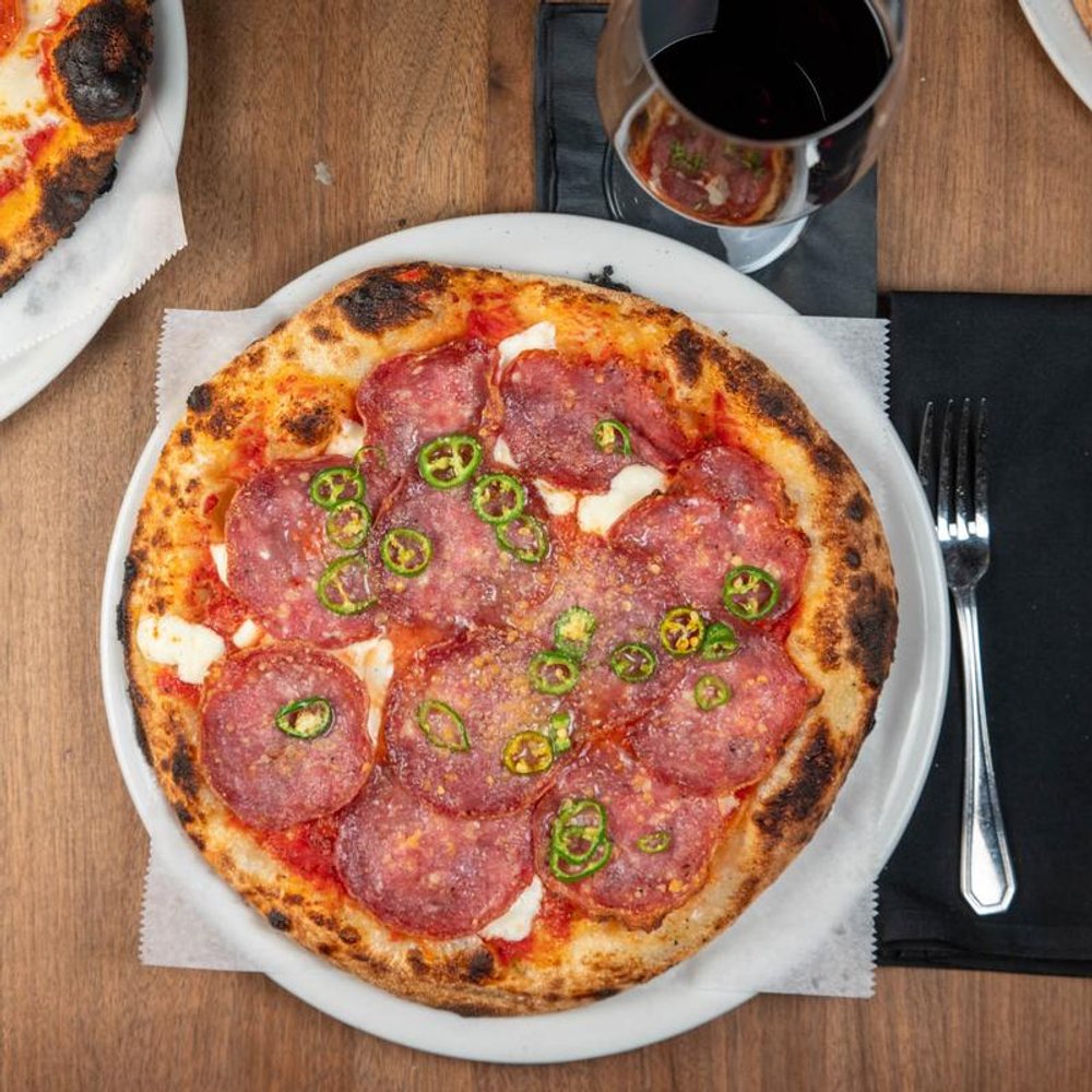 Spicy Soppressata Pizza Served With A Glass Of Red Wine.