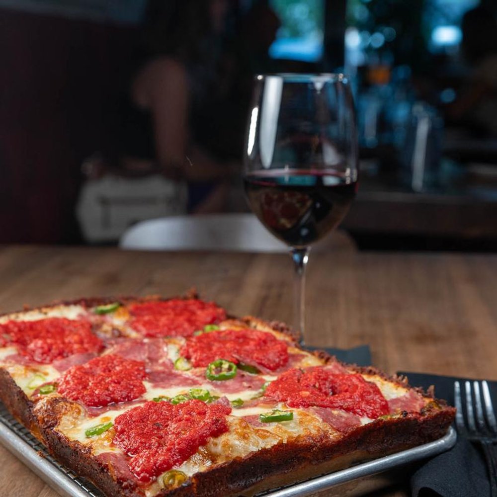 Square Soppresata Pizza With Serrano Peppers Served With A Glass Of Wine.