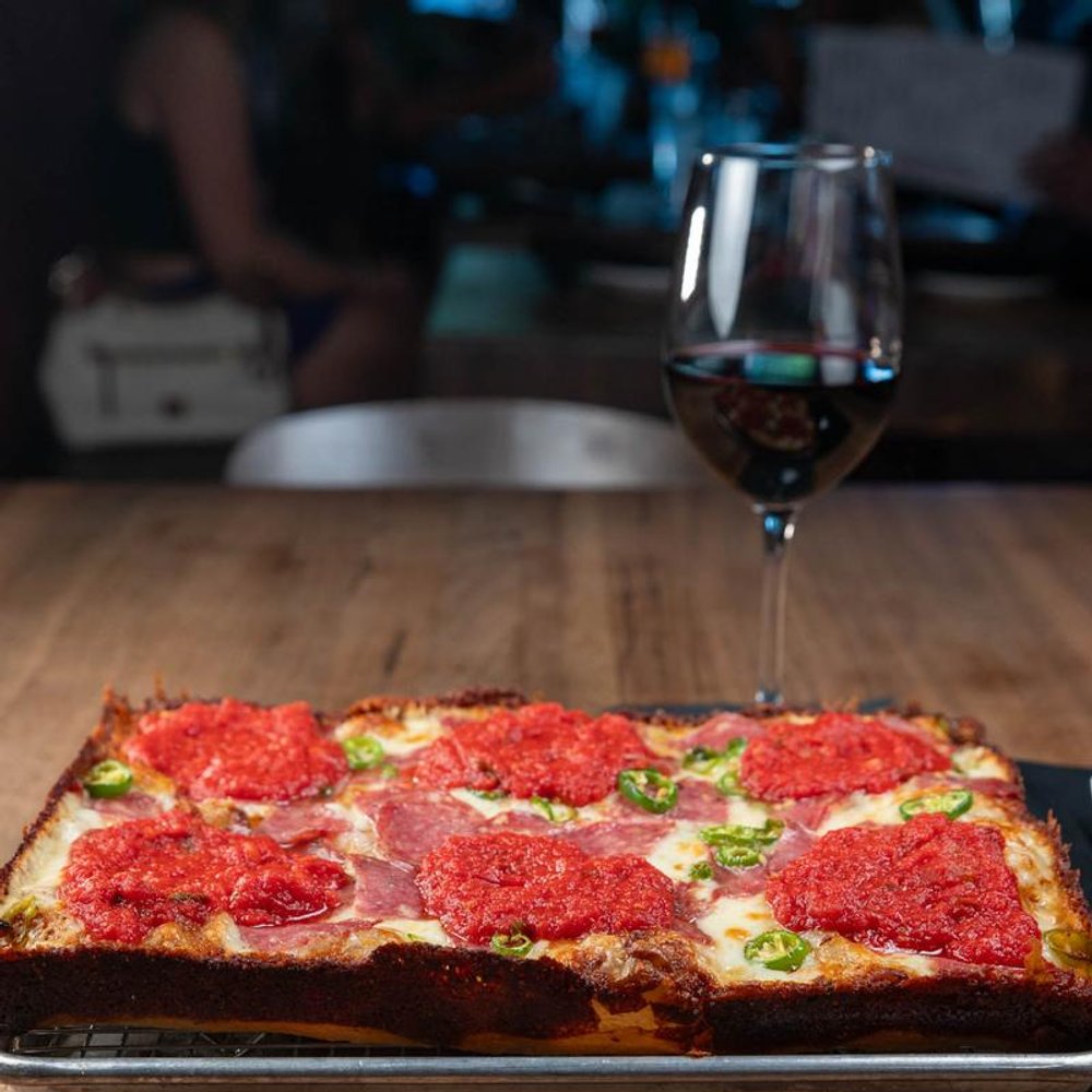 Square Soppressata Pizza On A Table With A Glass Of Red Wine.
