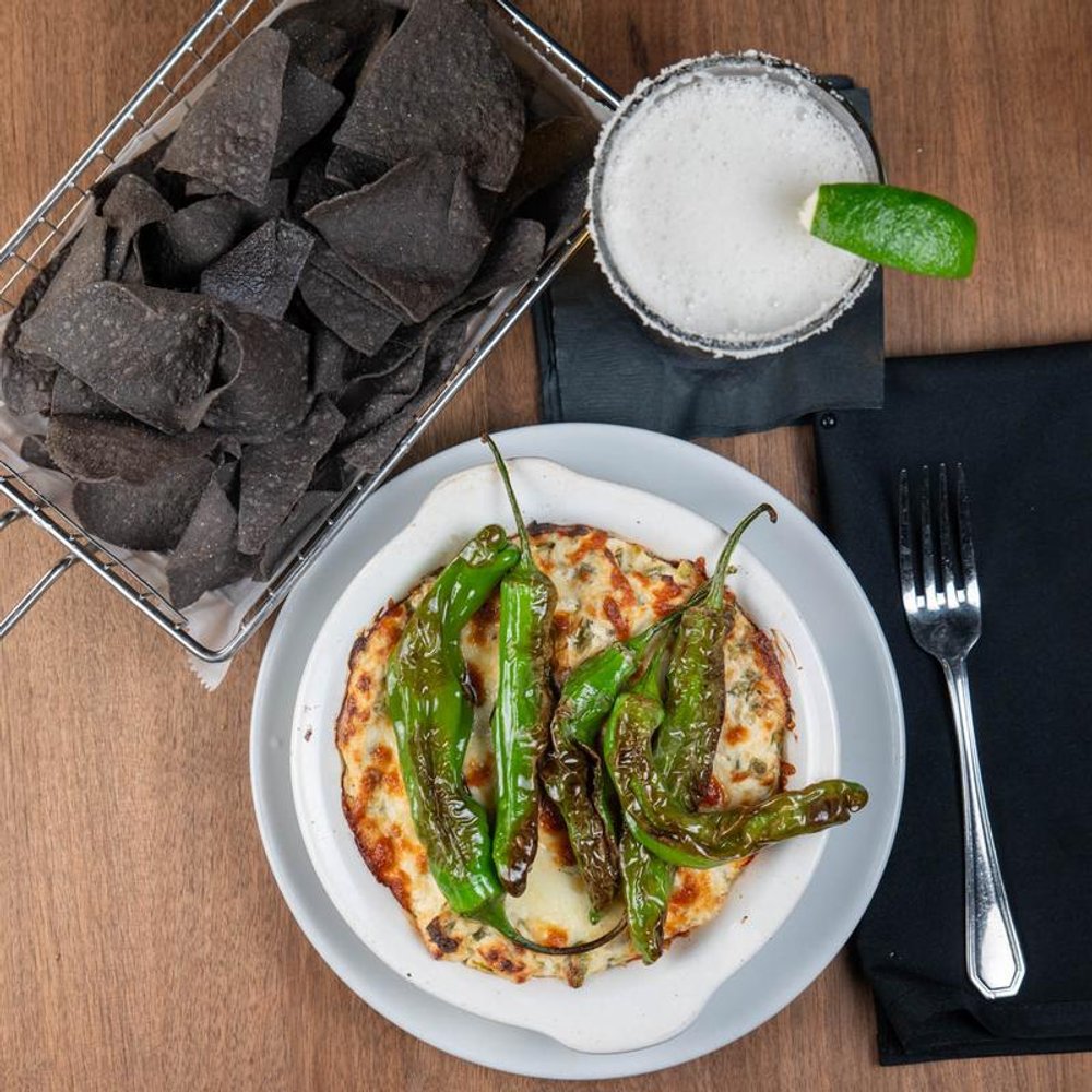 Top View Of Shishito Peppers With Blue Corn Chips And A Beer.