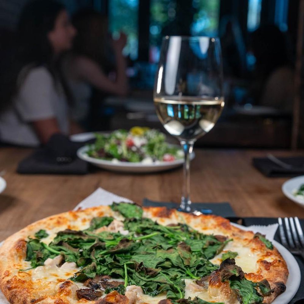 White Chicken Pizza With A Glass Of White Wine And A Salad In The Background.