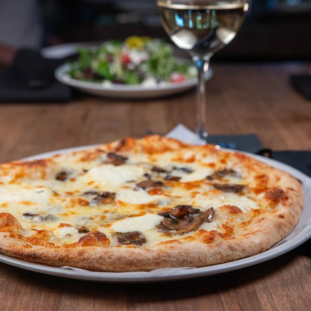 White Truffle Pizza Served With White Wine Other Food In The Background.